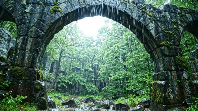 Ancient stone arches framing rain-filled forest depth