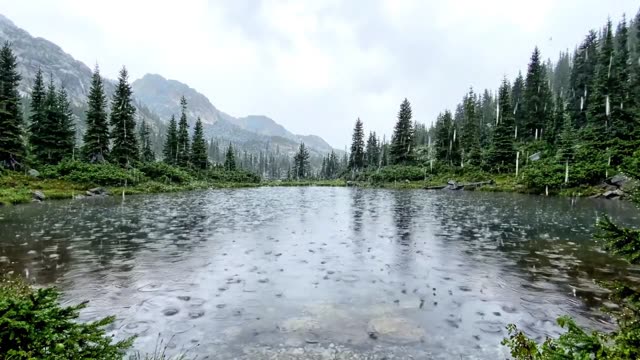 A still mountain tarn reflecting cloud with soft rain rings